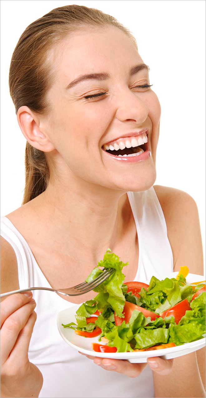 Mujer riendo sola con ensalada.