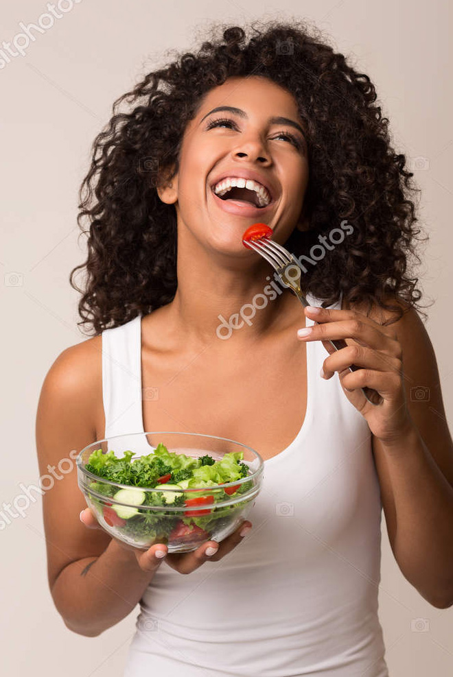 Mujer riendo sola con ensalada.